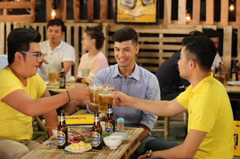 un groupe d'amis portant un toast avec de la bière Larue à Da Nang, Vietnam