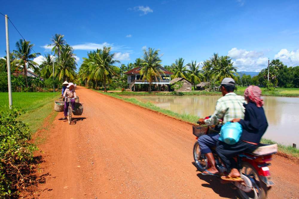 vélo et moto sur un chemin rouge à la campagne cambodgienne
