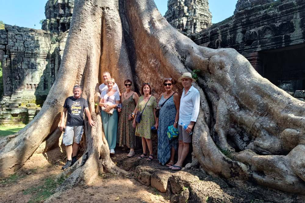 Voyageurs d'Asiatica Travel à côté d'un arbre géant dans un temple d'Angkor