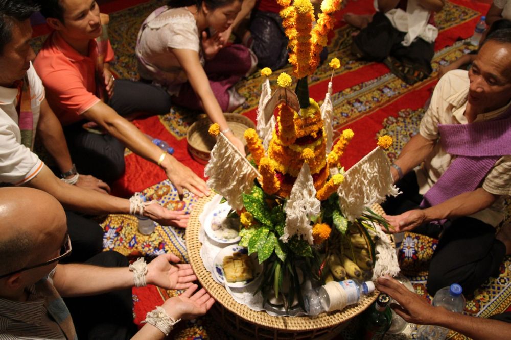 participants du baci se rassemblent autour du plateau d'offrandes, cérémonie du baci au Laos, voyage au Laos, culture laotienne