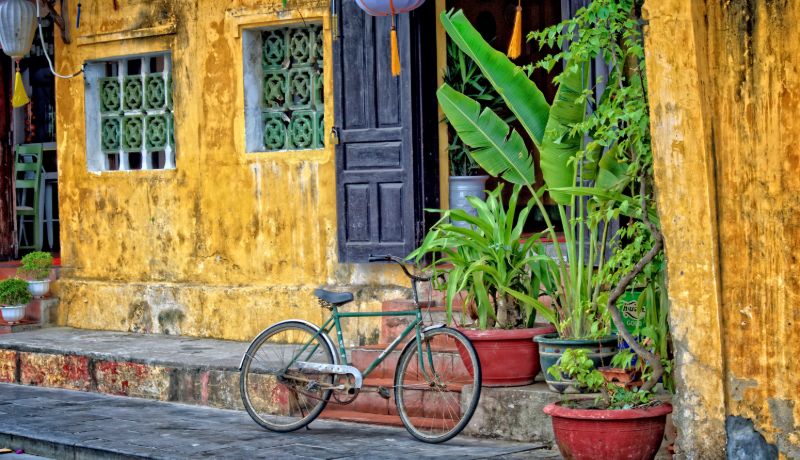 une maison à Hoi An de style ancien avec le mur jaune, des lanternes et des plantes en pot