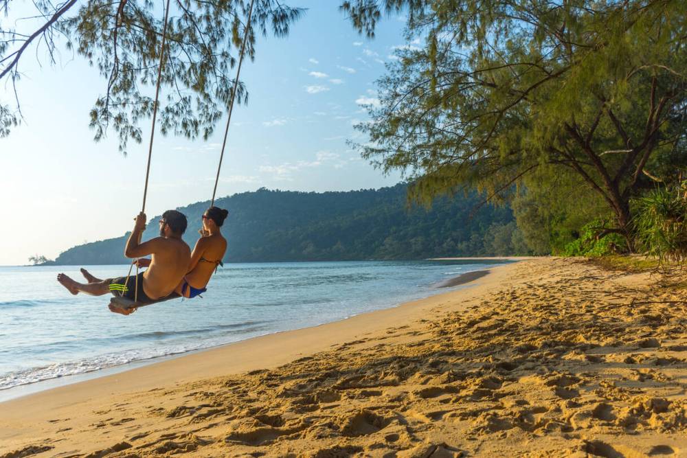 Un couple joue de la balançoire sur la plage de l'île de Koh Rong Samloem au Cambodge
