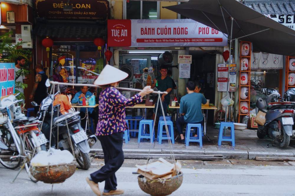 une vendeuse ambulante passe devant le restaurant du pho treo à Hanoi