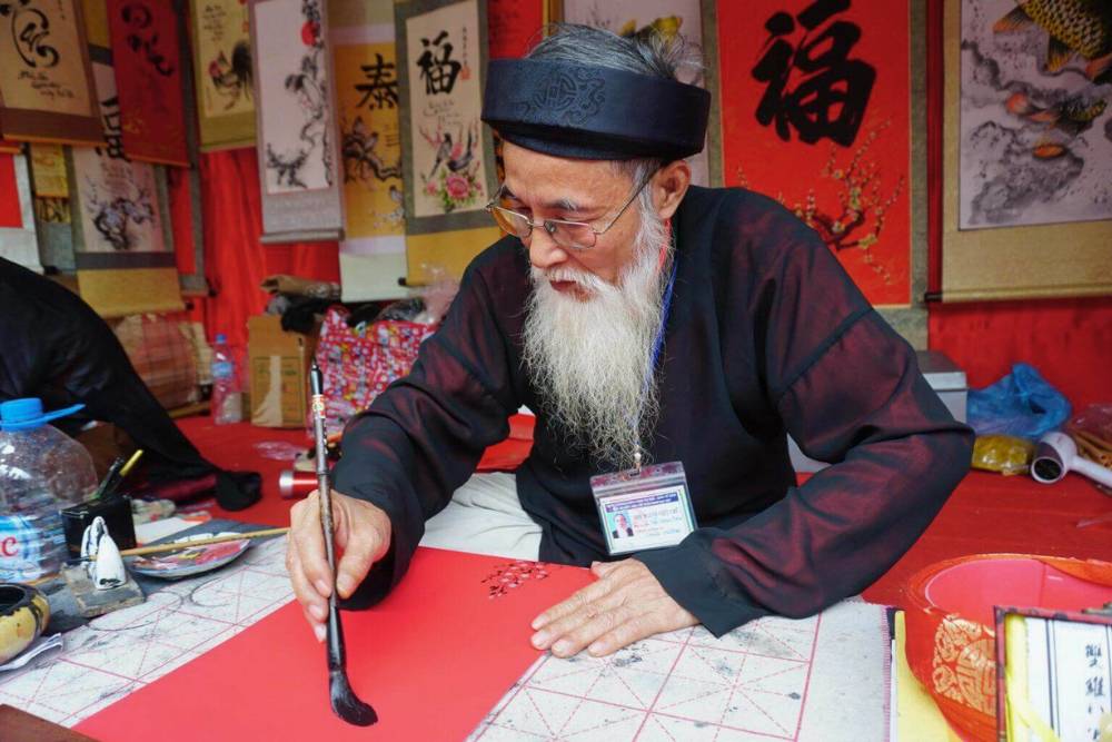 un caligraphe vietnamien écrit des vœux sur un papier rouge lors du Têt