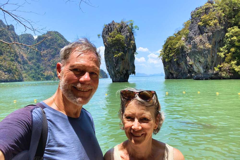 couple devant une formation rocheuse dans une baie de Thaïlande