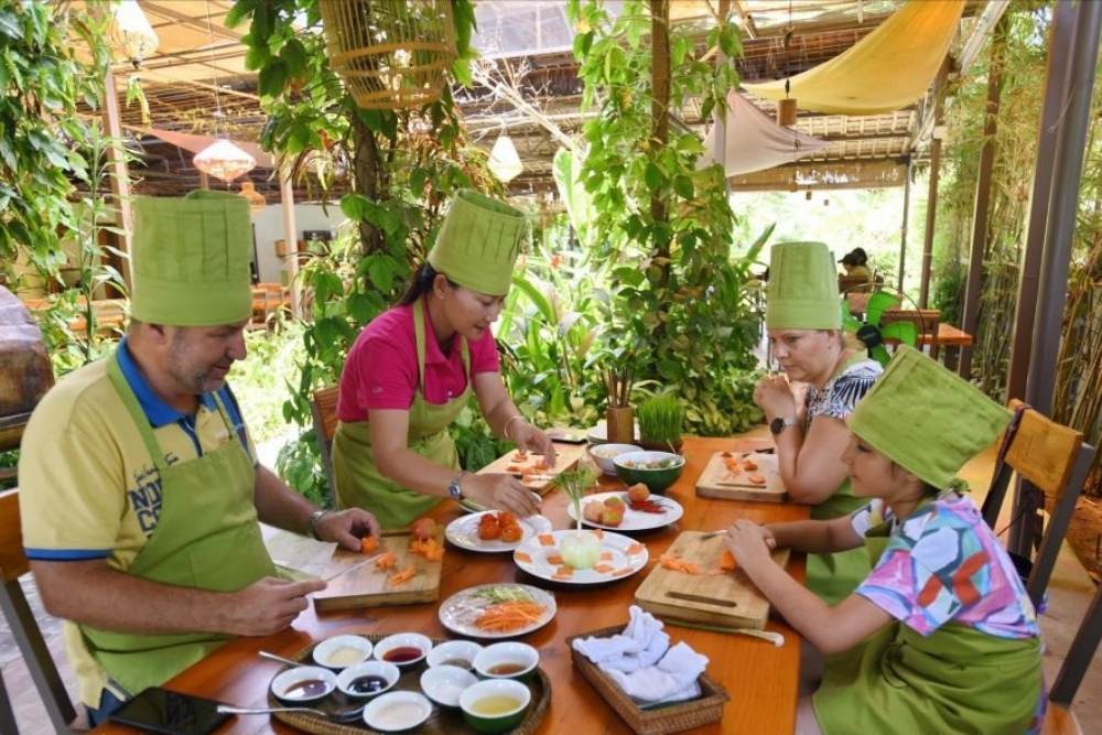 Les touristes découvrent la cuisine au village de Tra Que à Hoi An