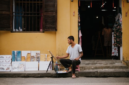 vacances vietnam, séjour au vietnam, hoi an, un artiste peint devant une ancienne maison